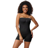 Woman wearing a black strapless bodysuit against a plain background