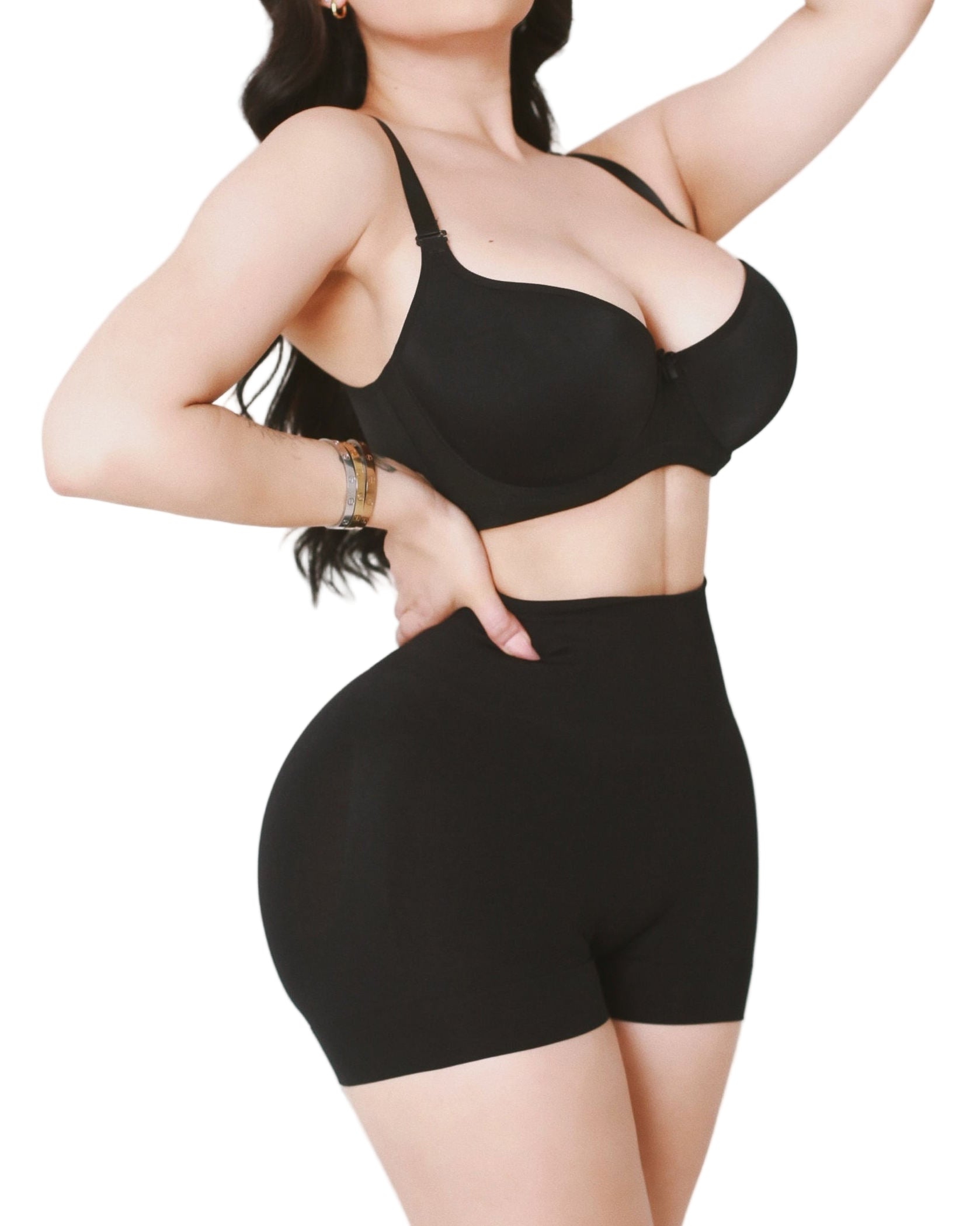 Person wearing a black sports bra and high-waisted shorts on a light background