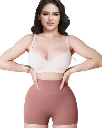 Woman wearing a white bra and brown shorts on a light pink background