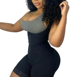 Person wearing a black bodysuit over a gray tank top against a plain background