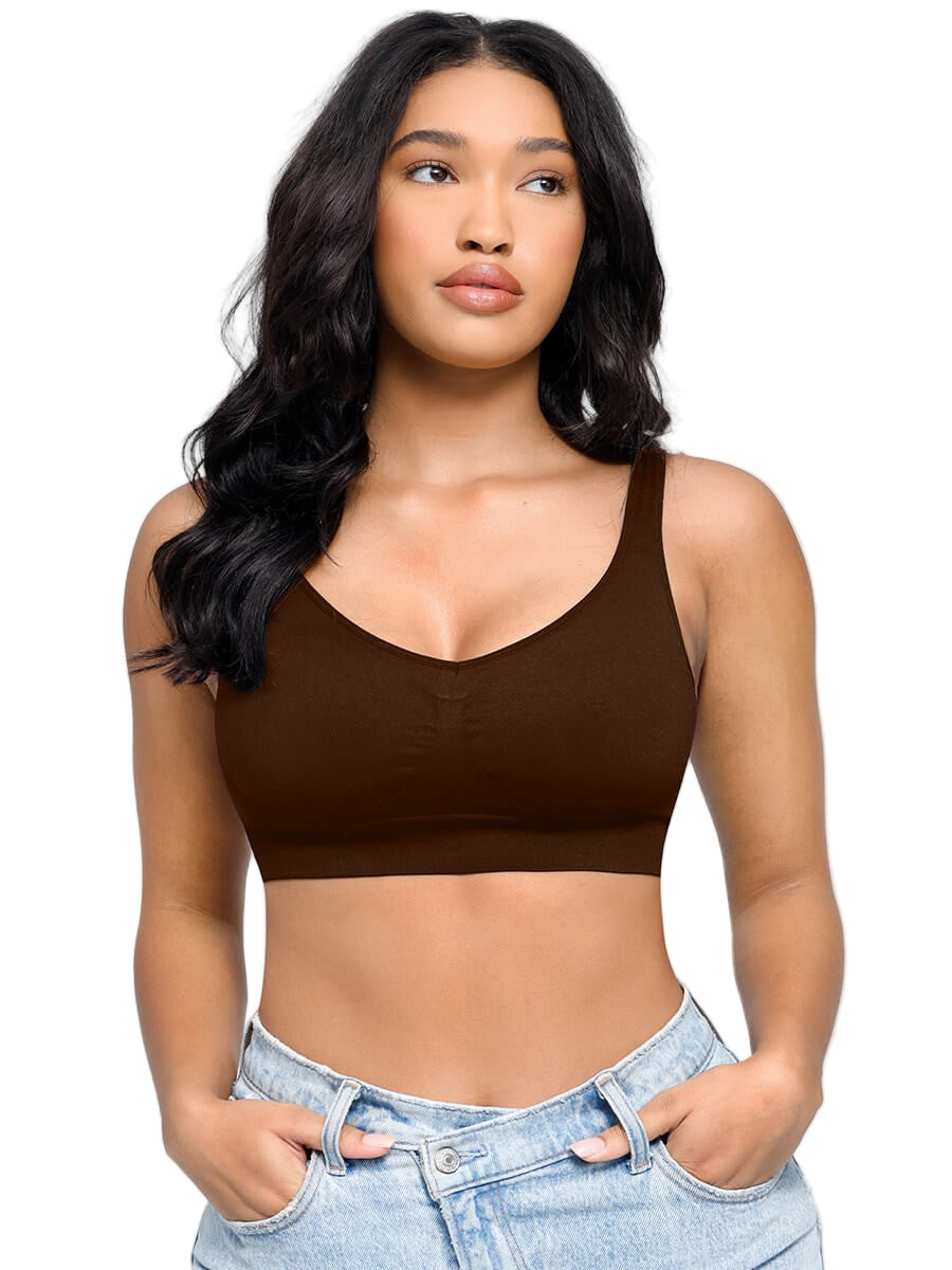 Woman wearing a brown crop top and light blue jeans against a plain background