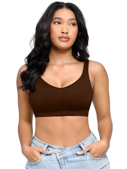 Woman wearing a brown crop top and light blue jeans against a plain background