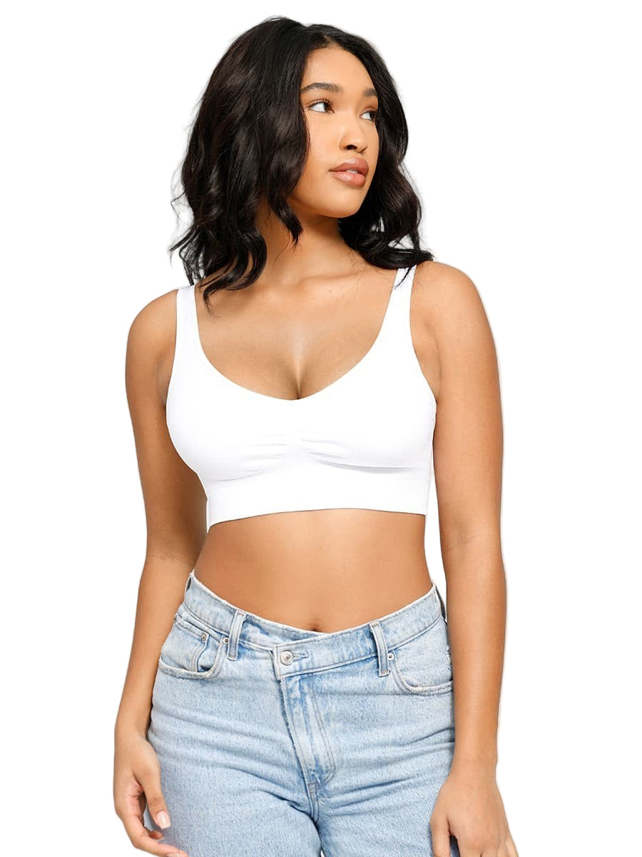 Woman wearing a white crop top and light blue jeans on a plain background