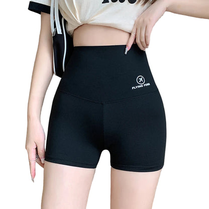 Person wearing black shorts with a logo on the side, standing indoors.