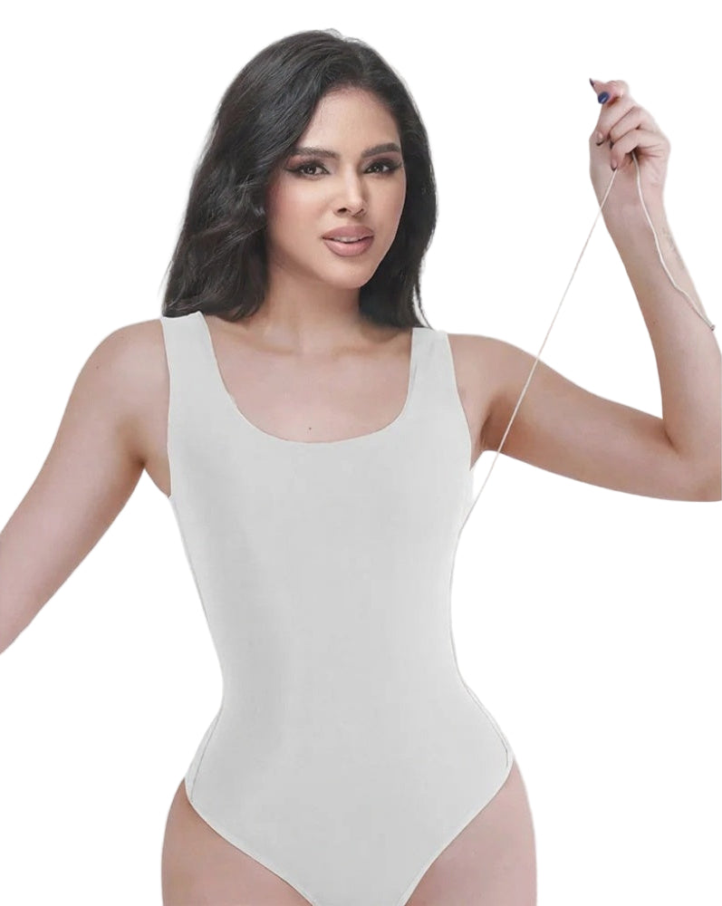 Woman wearing a white bodysuit against a light background