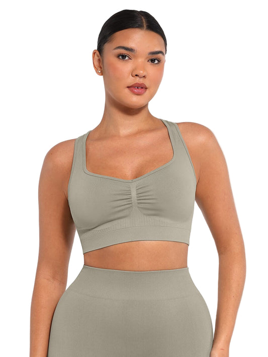 Woman wearing a green sports bra and leggings on a white background